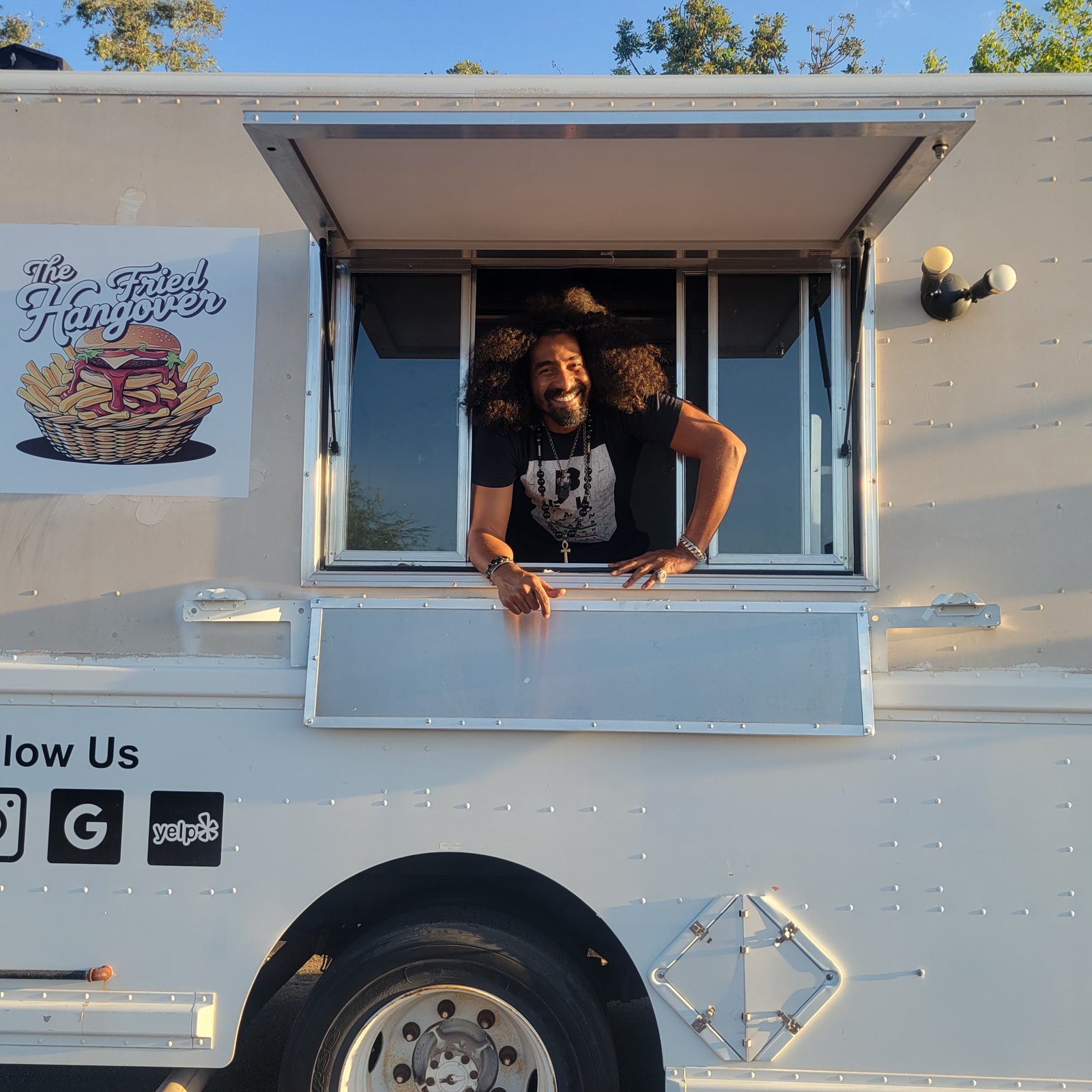 Grant Sing leaning out of the service window of The Fried Hangover food truck